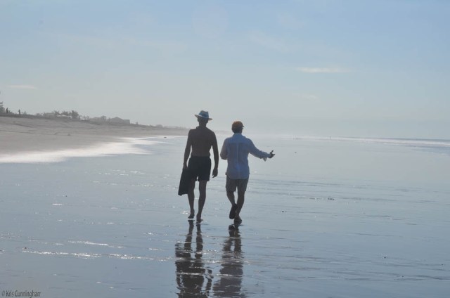 two friends walk down the beach